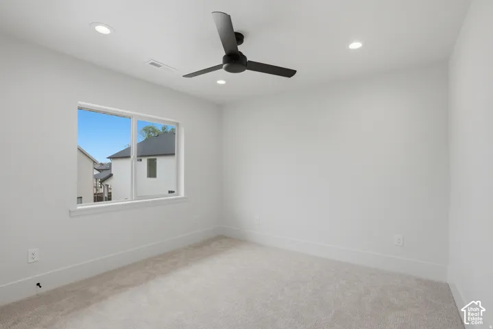 Neutral interior room featuring neutral carpeting, a black ceiling fan, and recessed lighting