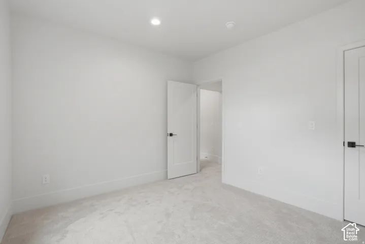 Neutral wall tones, wall-to-wall carpeting, recessed ceiling lighting, and solid-core interior doors with matte black hardware