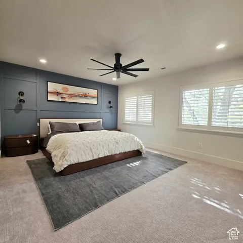 Accent wall with decorative moulding, recessed lighting, matte black ceiling fan, and plantation shutters
