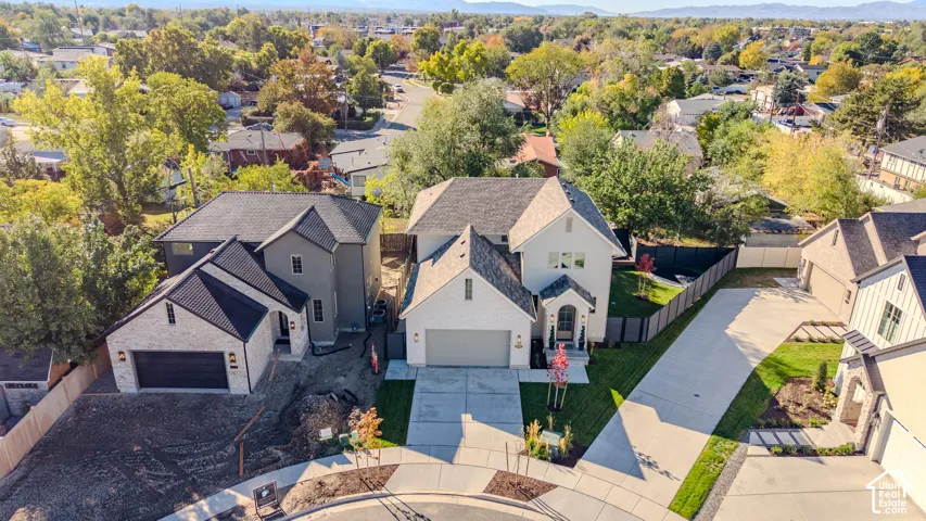Aerial perspective of multi-level residences featuring steep gable rooflines, mixed masonry and siding exteriors, attached multi-car garages, and concrete driveways situated within a suburban neighborhood