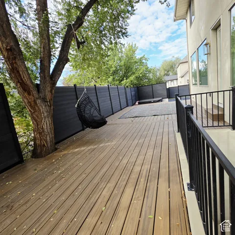Exterior deck featuring horizontal wood-finish planks, black metal railings, and a privacy fence