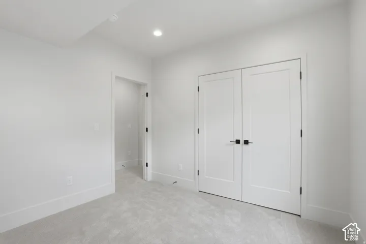 Neutral-toned carpeting, white shaker-style double doors, matte black hardware, recessed ceiling lighting, and smooth wall finish