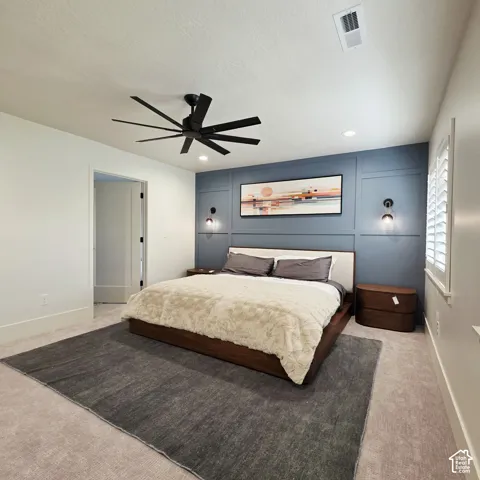 Blue panel accent wall, multi-blade matte black ceiling fan, dual wall-mounted light fixtures, and white plantation shutters
