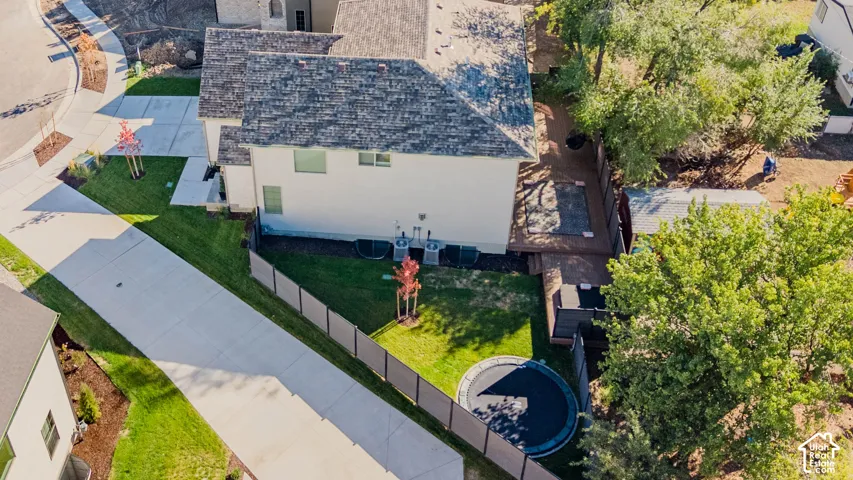 Aerial perspective featuring a multi-level wood deck, privacy fencing, manicured lawn, and mature trees