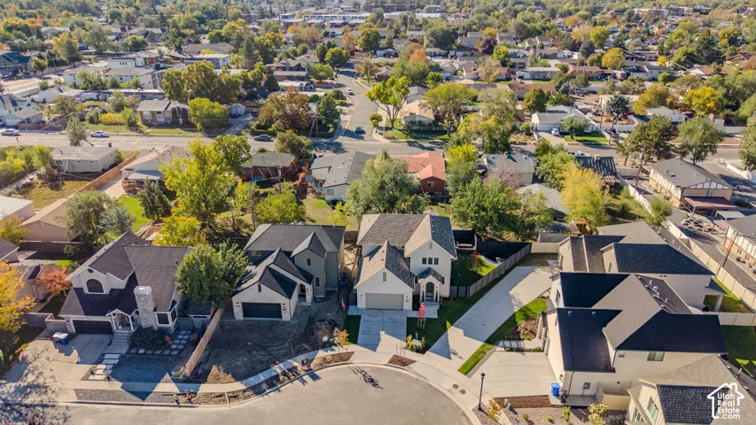 Aerial perspective featuring a multi-level residence with a multi-gable roofline, neutral siding, an attached garage, and a concrete driveway