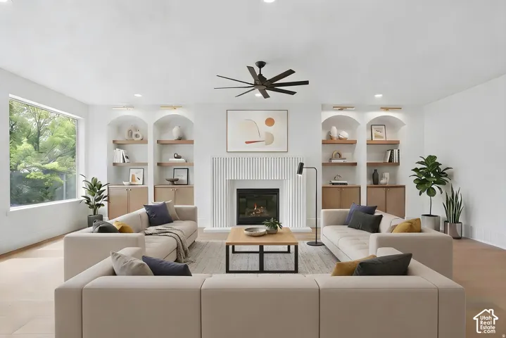 Living area featuring a fireplace with a textured vertical-slat surround, built-in arched display shelving, wood-finish flooring, and recessed lighting