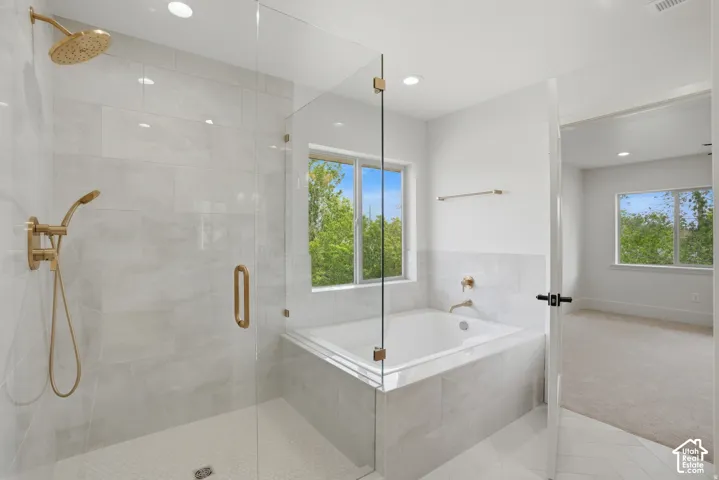 Walk-in shower with gold-finish hardware, glass enclosure, large-format tile wall surround, built-in soaking tub, and herringbone pattern tile flooring