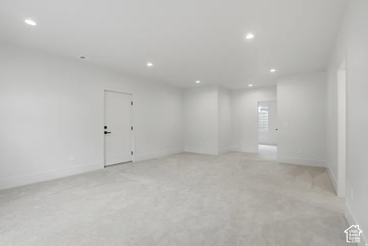 Neutral interior featuring plush wall-to-wall carpeting, recessed ceiling lighting, and a solid-core interior door with matte black hardware