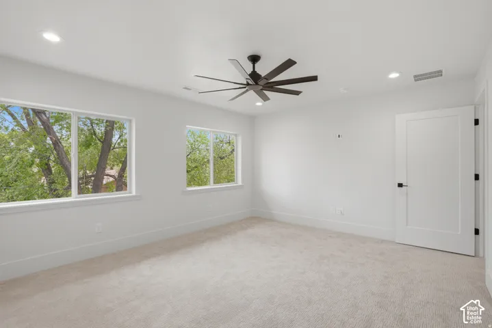 Neutral-toned carpeting, multi-blade ceiling fan, recessed lighting, and white interior doors with matte black hardware