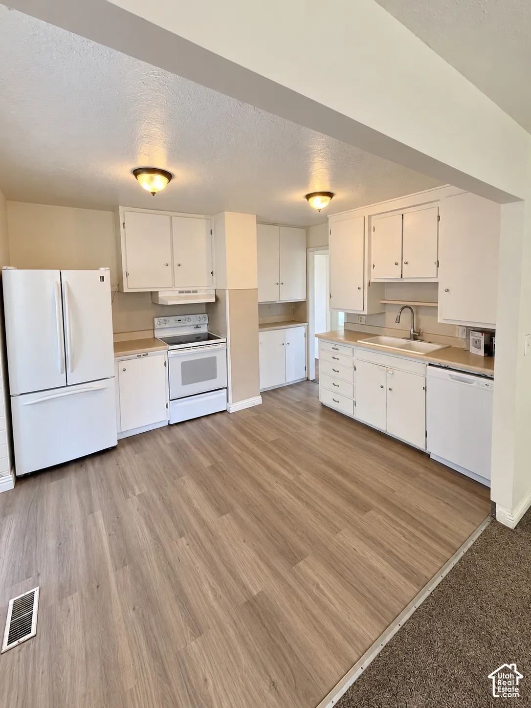 Kitchen featuring wood-finish flooring, white cabinetry, a double basin sink, and ceiling-mounted light fixtures