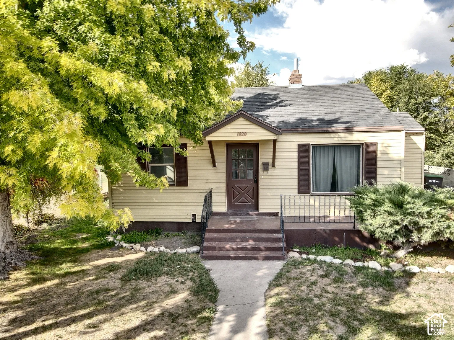 Siding exterior with contrasting shutters, mature front yard tree, and an inviting walkway leading to the entry