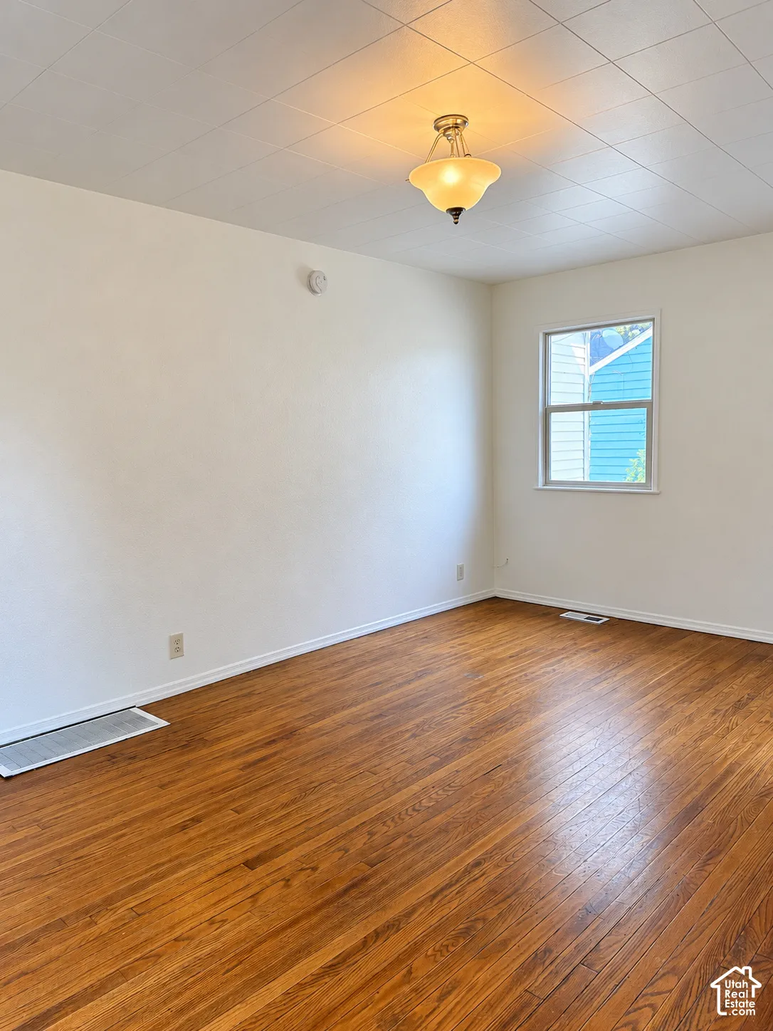 Wood-finish flooring with white baseboards, recessed window, and flush mount lighting