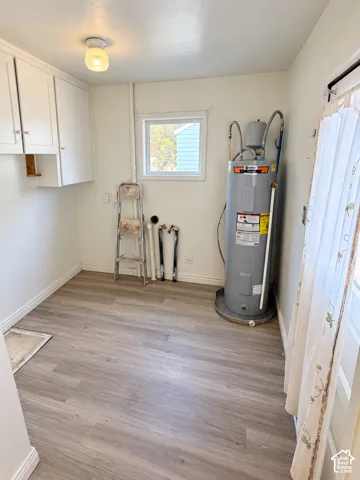 Neutral-toned wood-finish flooring, white walls, and a window with natural light