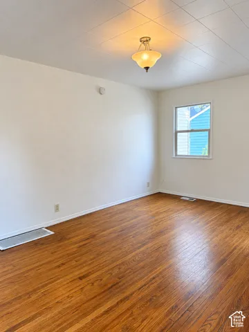 Wood-finish flooring with white baseboards, recessed window, and flush mount lighting