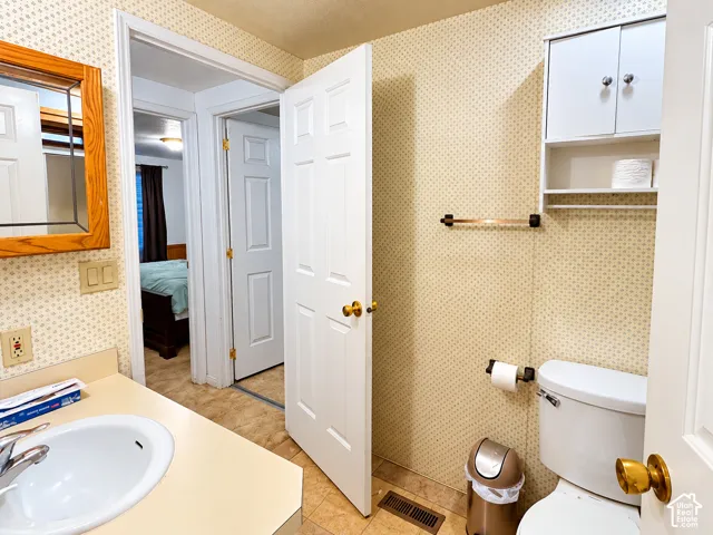 Bathroom featuring a solid-surface vanity countertop with an integrated basin, a wood-frame wall mirror, wall-mounted storage cabinetry, and a standard-height toilet