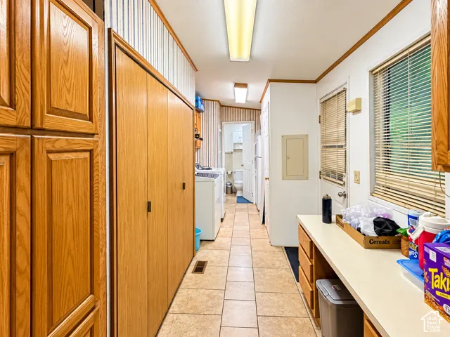 Utility room featuring ceramic tile flooring, extensive wood-finish cabinetry, a built-in countertop workspace, and dual flush-mount ceiling lighting fixtures