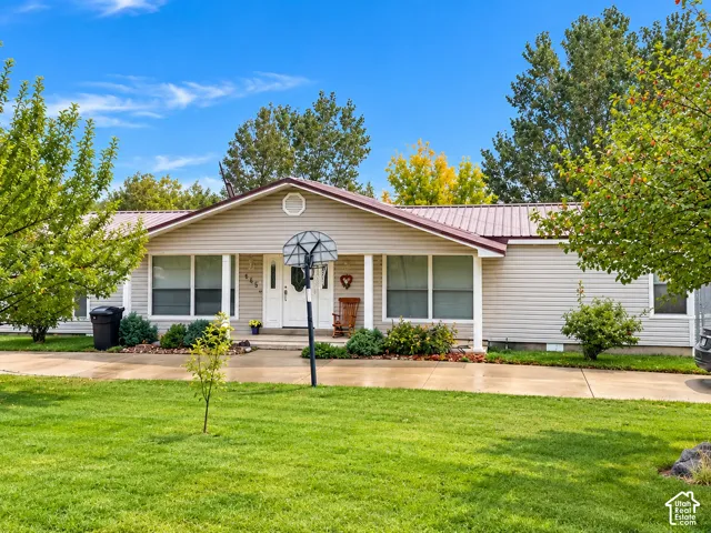 Ranch-style exterior featuring light-colored horizontal siding, a metal roof, a covered front entryway with white columns, and a concrete driveway