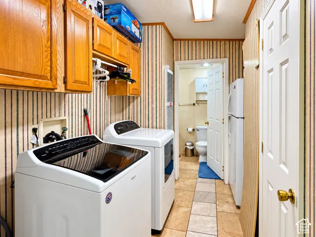 Laundry area featuring wood-finish wall cabinetry, an integrated garment rod, and tile flooring