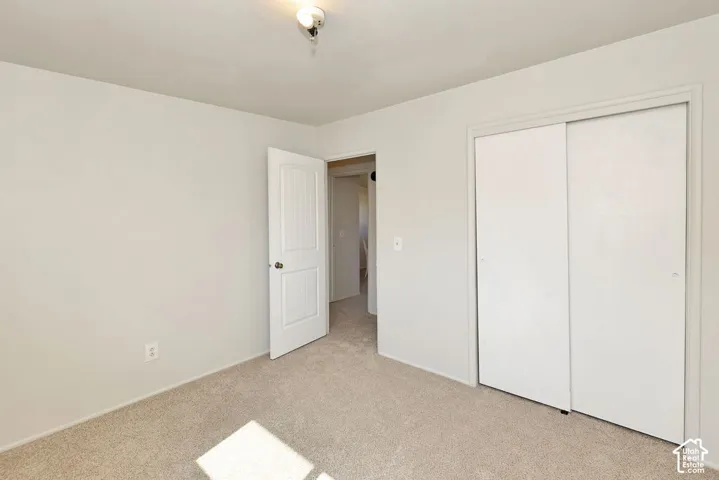 Neutral tone wall paint, carpeted flooring, white interior door, and white sliding closet doors