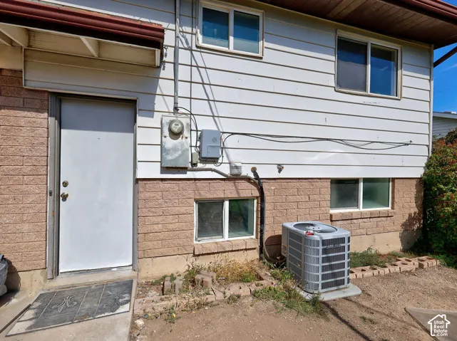 White siding exterior with brick foundation, featuring multiple windows and an exterior access door