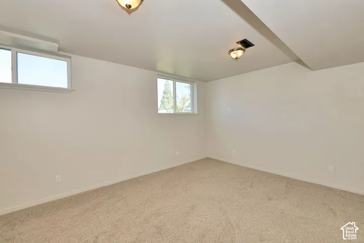 Carpeted room featuring two egress windows and two ceiling-mounted light fixtures
