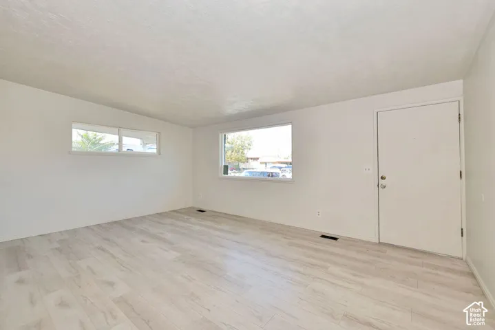 Bright interior with light wood-finish flooring, white walls, and multiple windows