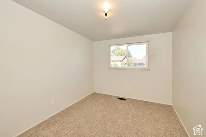 Neutral wall color, carpet flooring, window with white trim, and ceiling-mounted light fixture