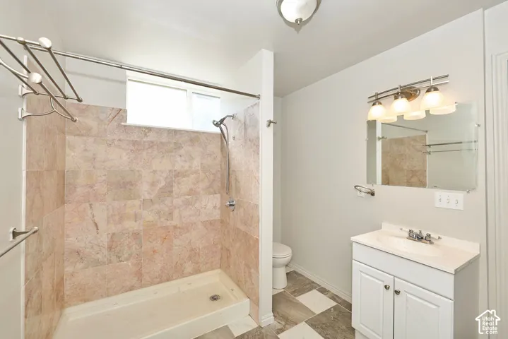 Tile shower surround with a window, white vanity with an integrated sink, wall-mounted mirror, and a three-light fixture