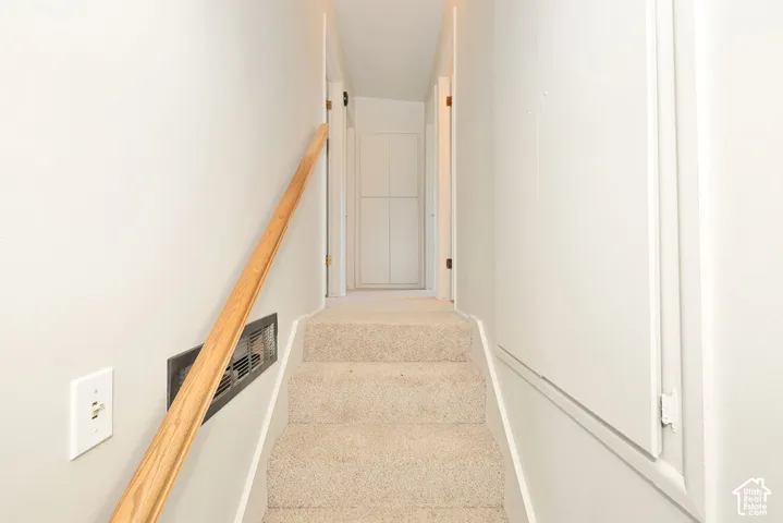 Carpeted stairway with a wooden handrail