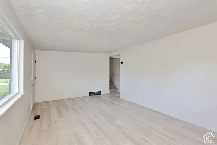 Light-toned wood-finish flooring, white painted walls, and a large window