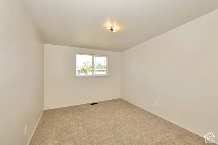 Neutral wall color, carpeted flooring, and a single window with white trim