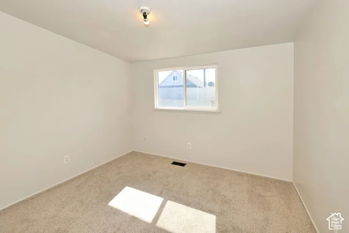 Carpeted room with a single window, white walls, and a ceiling-mounted light fixture