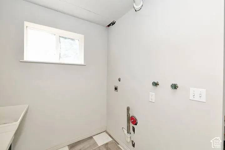 Utility room featuring a window, utility sink, and wall-mounted electrical outlets