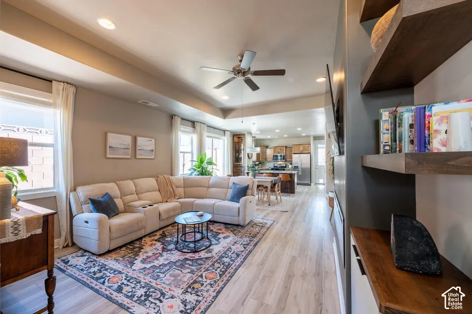Living area featuring tray ceilings, recessed lighting, wood-finish flooring, and built-in floating shelving with cabinetry
