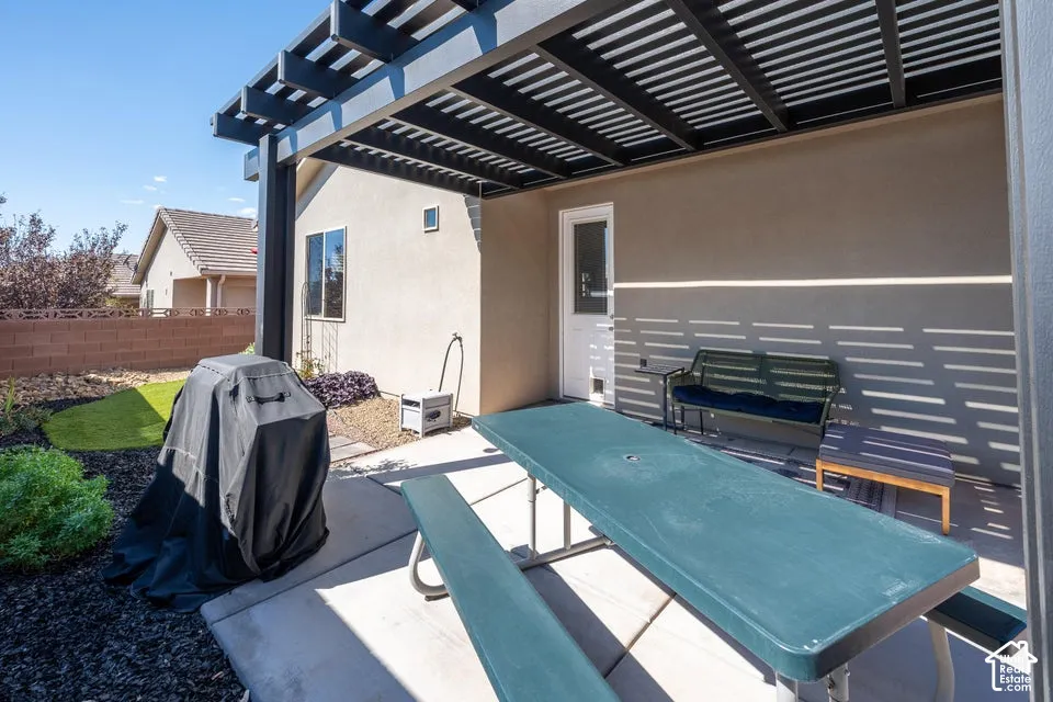 Covered patio featuring a metal pergola, concrete flooring, exterior-grade door, and masonry perimeter wall