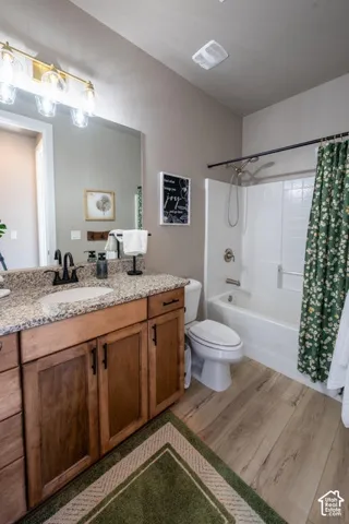 Bathroom featuring wood-finish cabinetry, stone-surface countertop, oval undermount sink with matte black hardware, and a white tub-shower combination