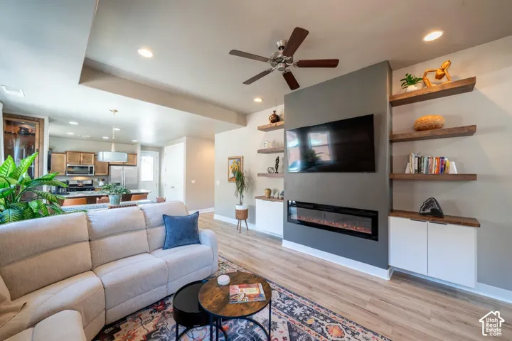 Floor-to-ceiling accent wall featuring a linear electric fireplace, custom white cabinetry, and tiered natural wood shelving, finished with recessed lighting and wood-finish flooring
