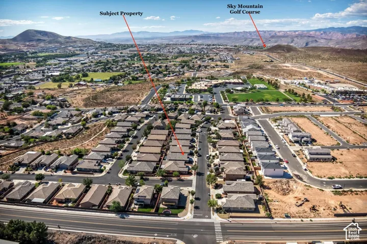 Aerial perspective of residential property featuring a composition-shingle roof, paved street access, and a mountain range backdrop