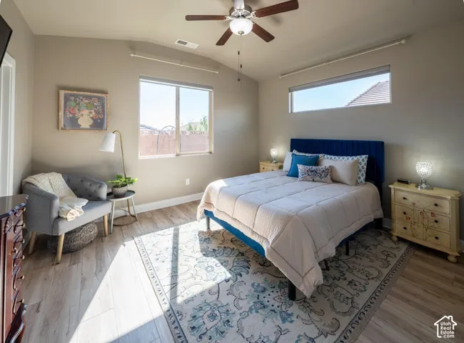 Vaulted ceilings with a central lighted ceiling fan, wood-finish flooring, and horizontal clerestory windows