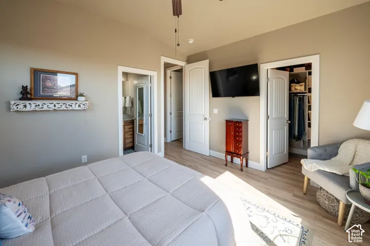 Vaulted ceilings featuring wood-finish flooring, white arched-panel doors, and built-in closet shelving