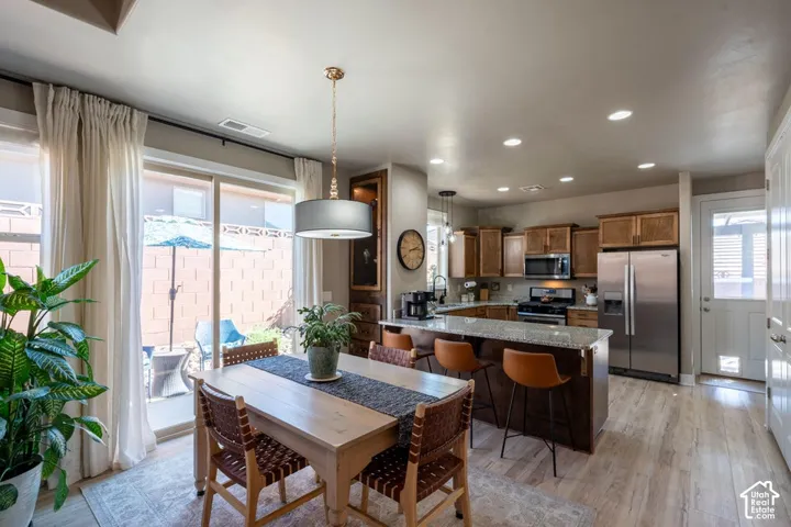 Kitchen featuring wood cabinetry, stone-surface breakfast bar, stainless steel appliances, recessed lighting, and wood-finish flooring
