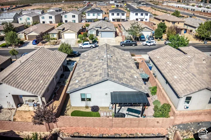Stucco exterior residence featuring a concrete tile roof, enclosed rear yard with masonry perimeter walls, synthetic turf lawn, and a metal-frame patio cover
