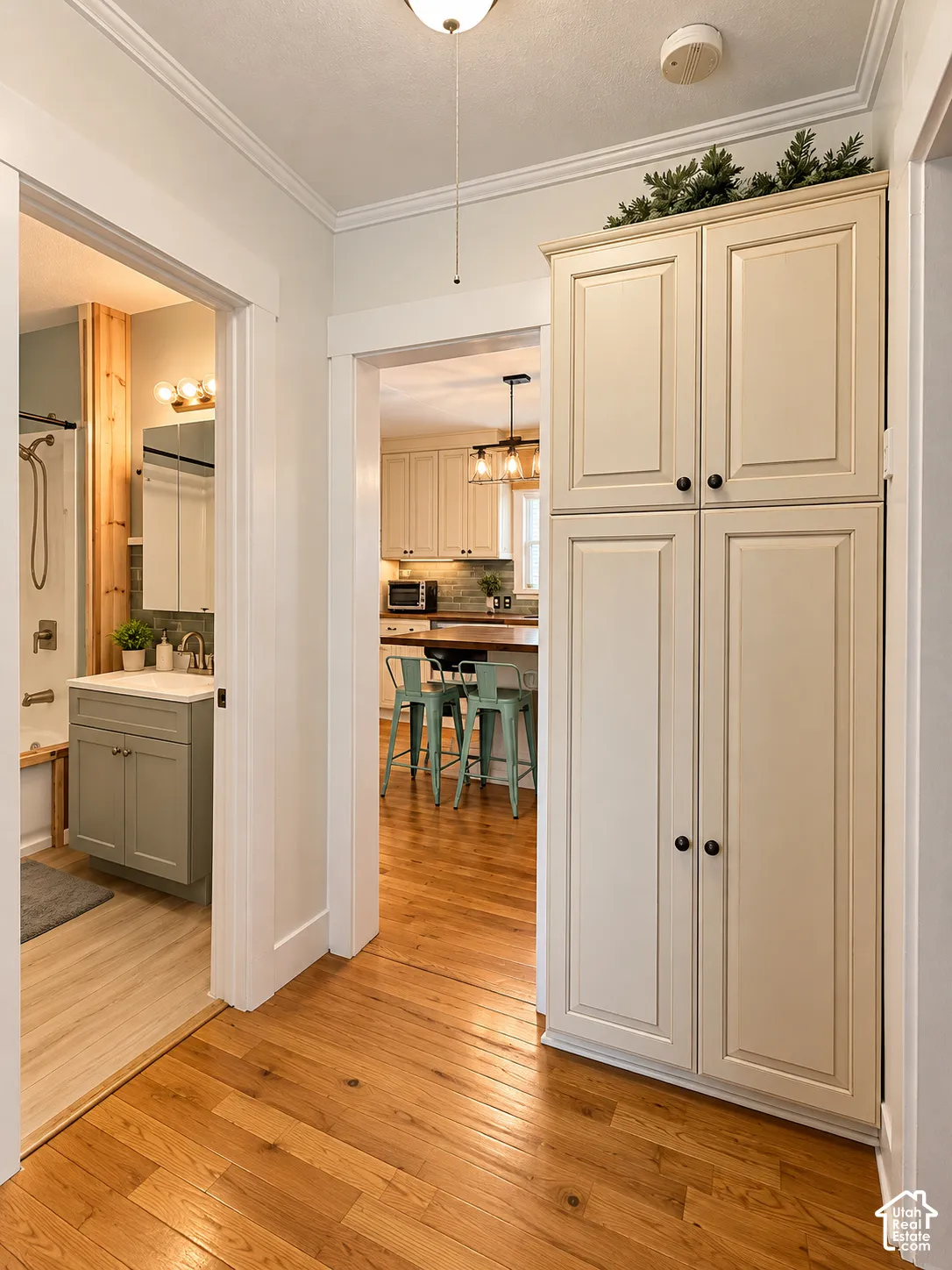 Full-height cream-colored cabinetry with recessed panel doors, rich wood-finish flooring, and crown molding