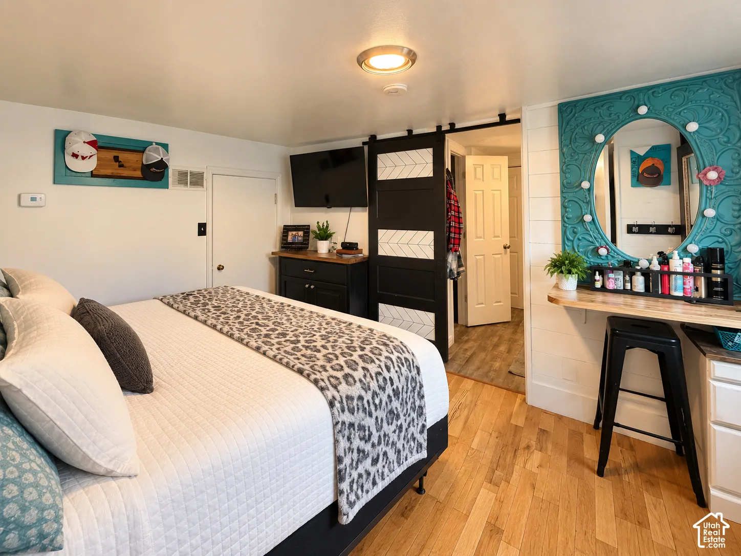 Wood-finish flooring, custom built-in vanity with integrated lighting, shiplap wall accents, and a sliding barn door with decorative patterned inlays