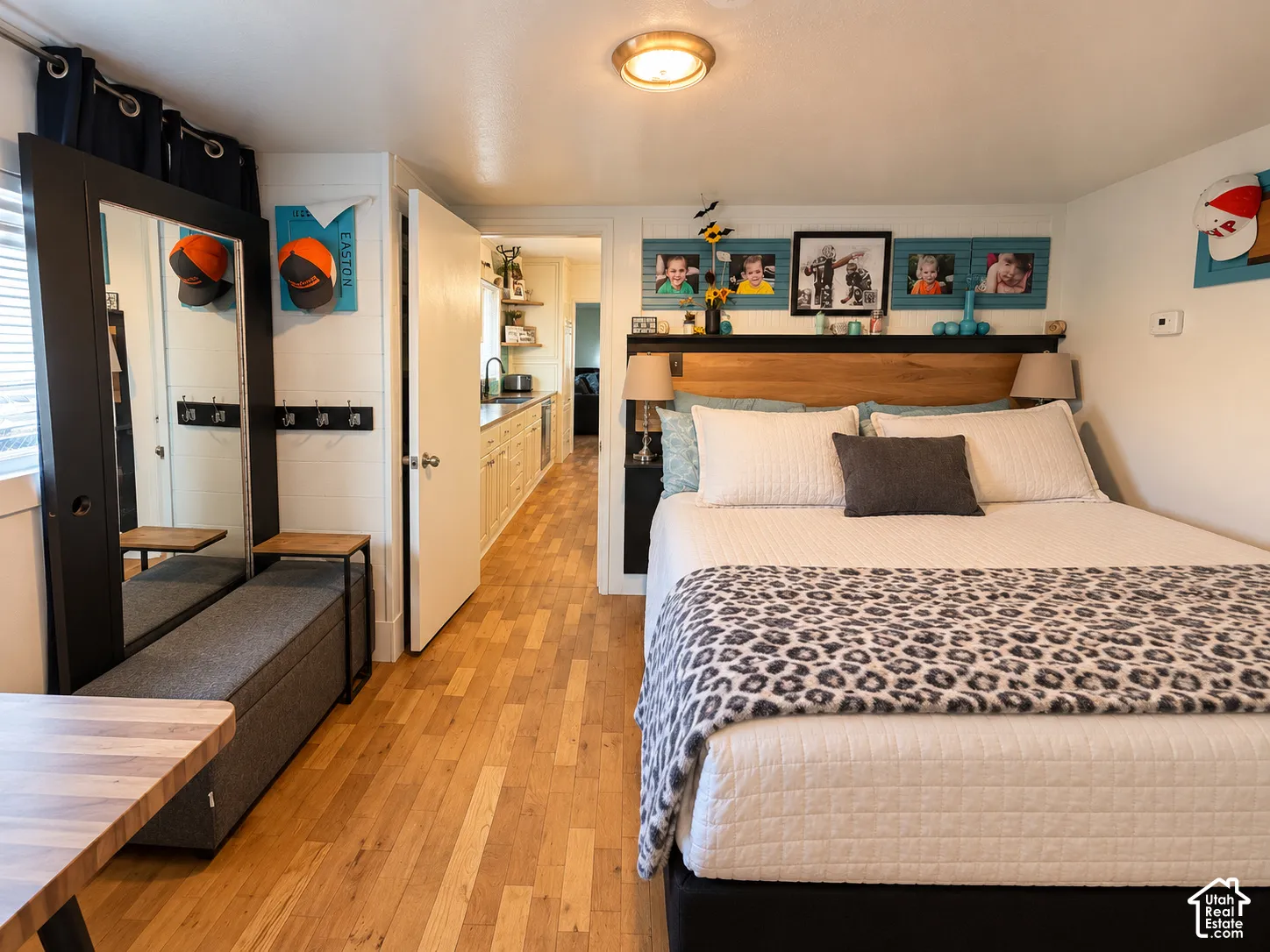 Wood-finish flooring, white shiplap walls, built-in black headboard with integrated shelving, and a full-length mirror with a black frame