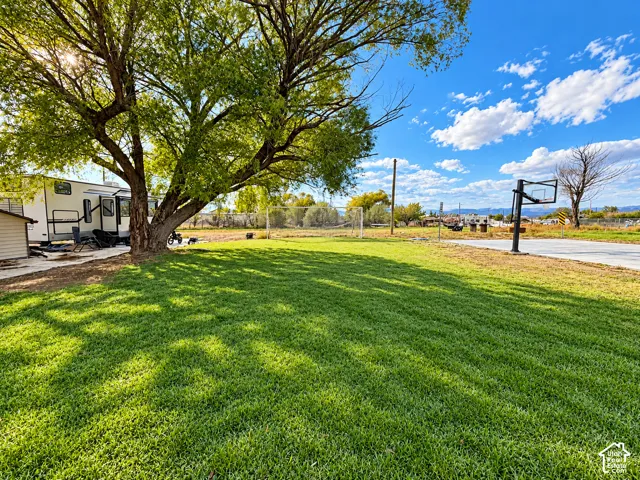 Expansive grounds featuring a manicured lawn, mature trees, a concrete sports court, and a goal post