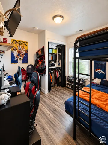 Bedroom featuring wood-finish flooring, a recessed closet with built-in shelving, a double-hung window, and flush-mount overhead lighting