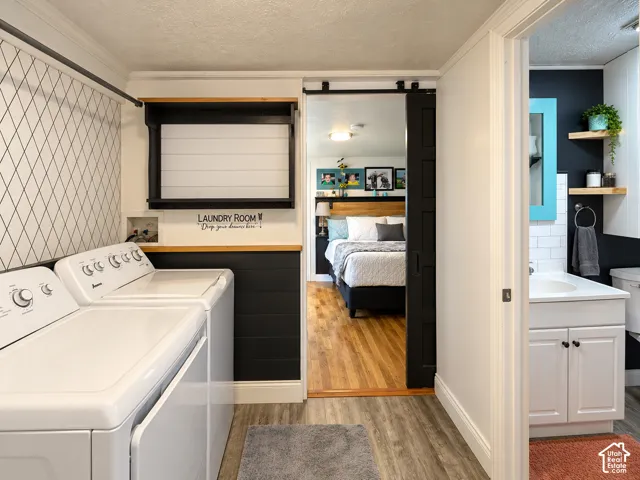 Laundry space featuring black horizontal plank paneling, geometric patterned accent wall, built-in wall shelving, and sliding barn door hardware