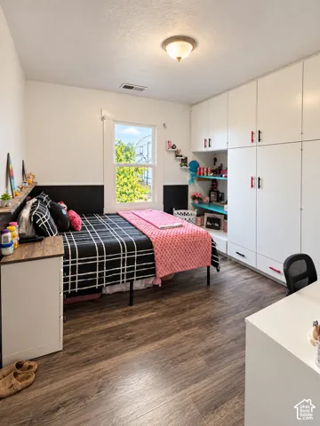 Wood-finish flooring, floor-to-ceiling built-in white cabinetry, and a black wainscot wall accent