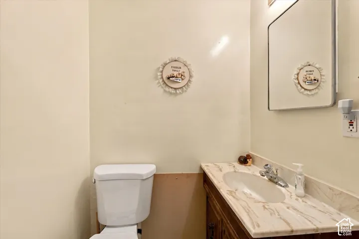 Bathroom vanity featuring a light-toned countertop with an integrated basin, metal faucet hardware, wood-finish cabinetry, and a rectangular wall-mounted mirror